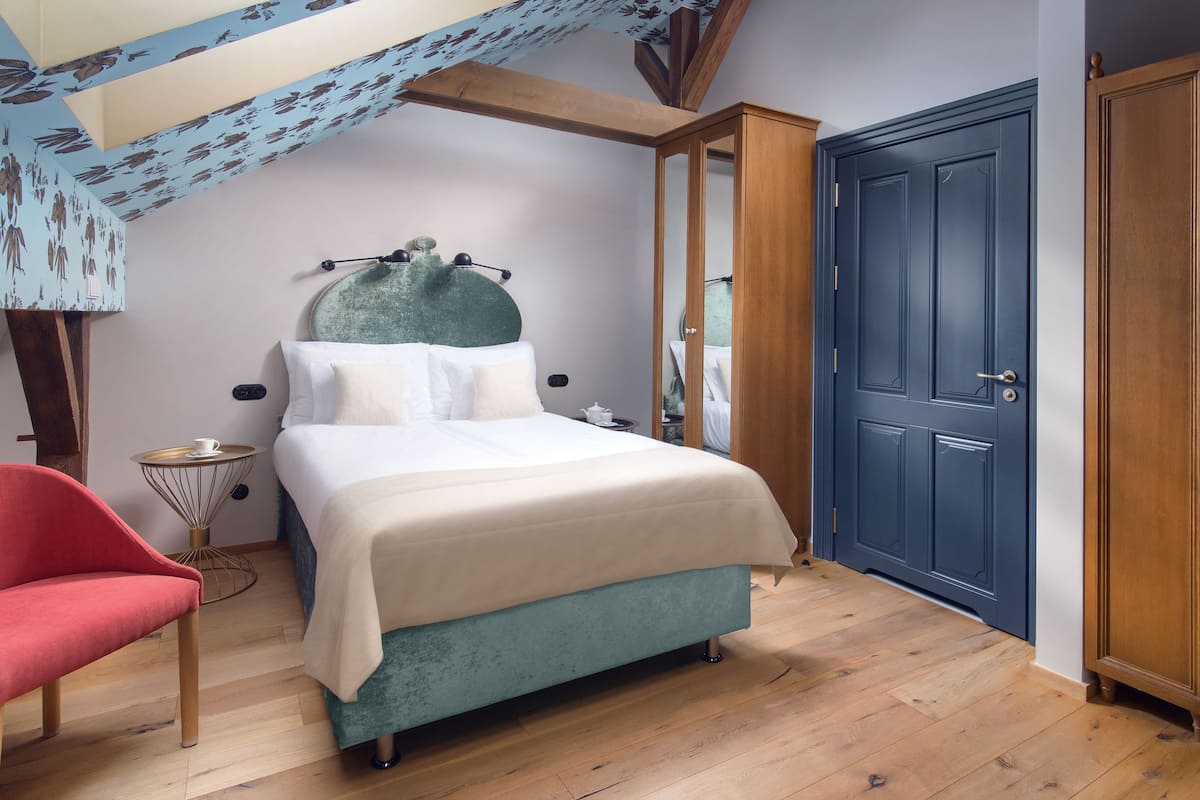 Une chambre à coucher avec un lit, une chaise rouge, une armoire en bois et une porte bleue.