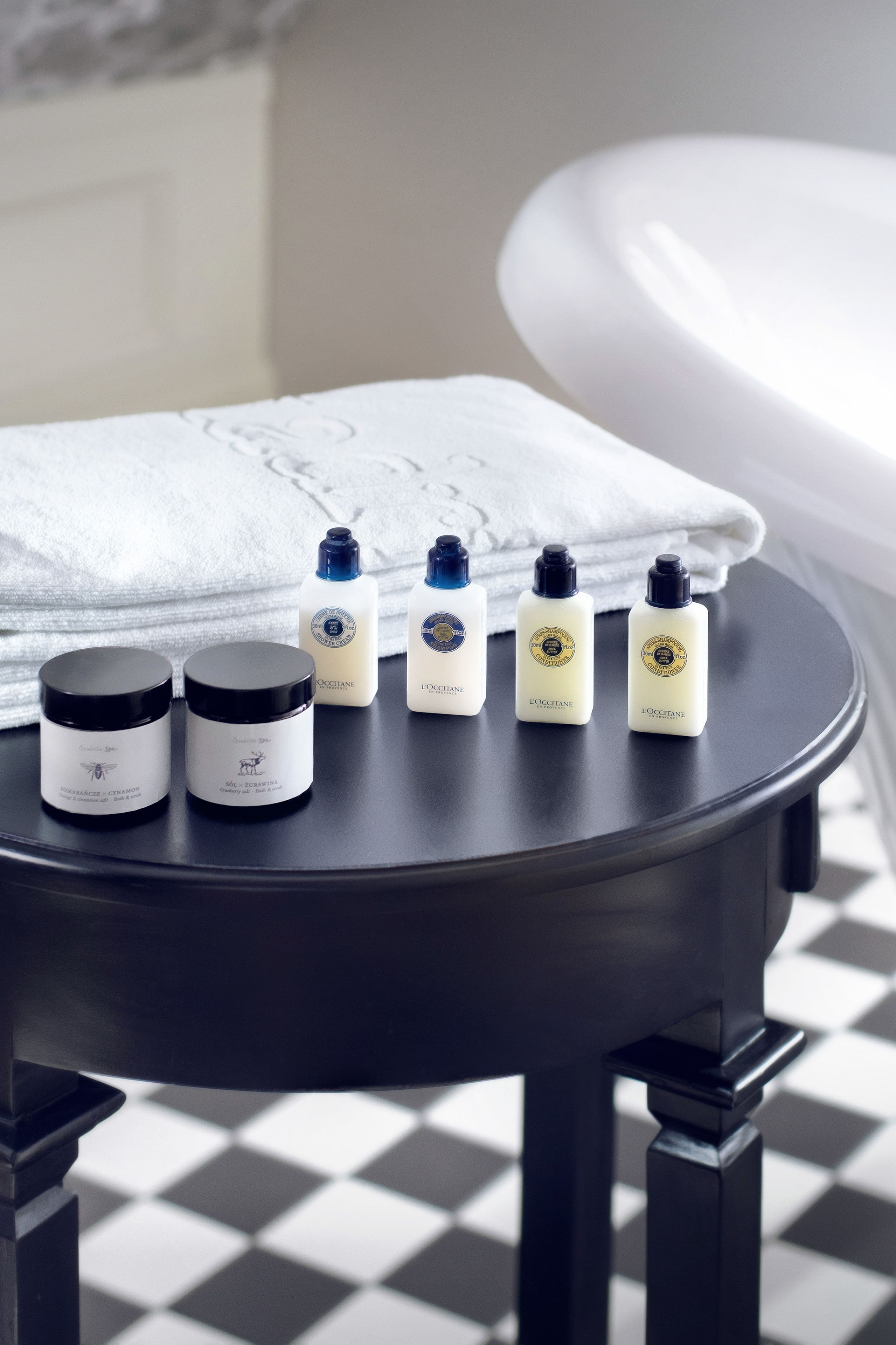 A bathroom with a black table holding toiletries, a white towel, and a bathtub.