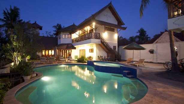 Una casa de dos pisos con piscina, un balcón y una escalera que lleva al piso superior.
