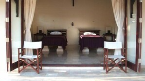Una habitación con dos camas, una mesita y dos sillas.