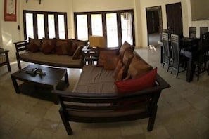 Uma sala de estar com sofá, mesa de centro e área de jantar com cadeiras.