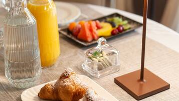 A breakfast setting with croissants, juice, and a fruit platter on a table.