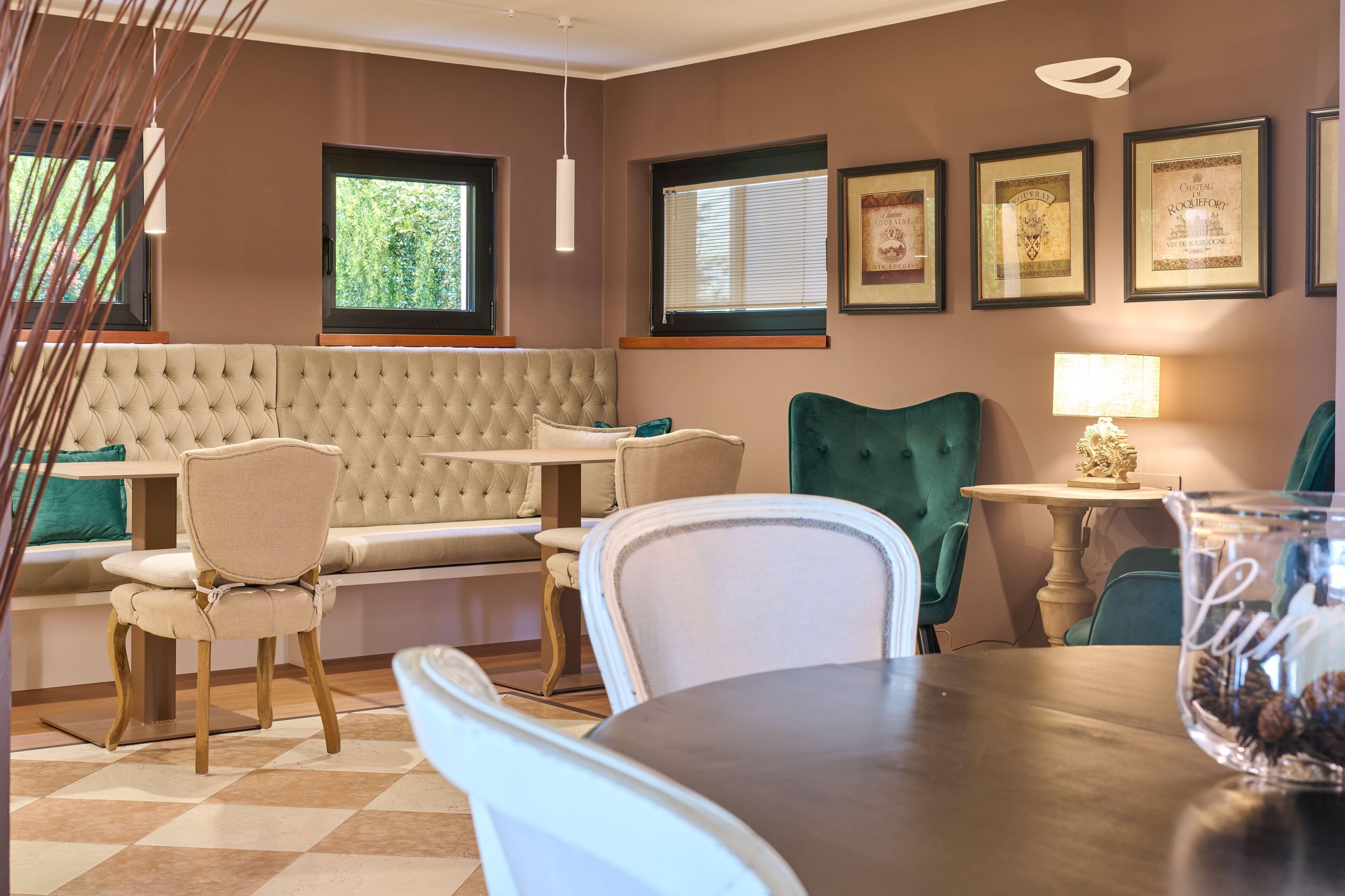 A dining area with a round table, chairs, a cushioned bench, and framed pictures on the wall.