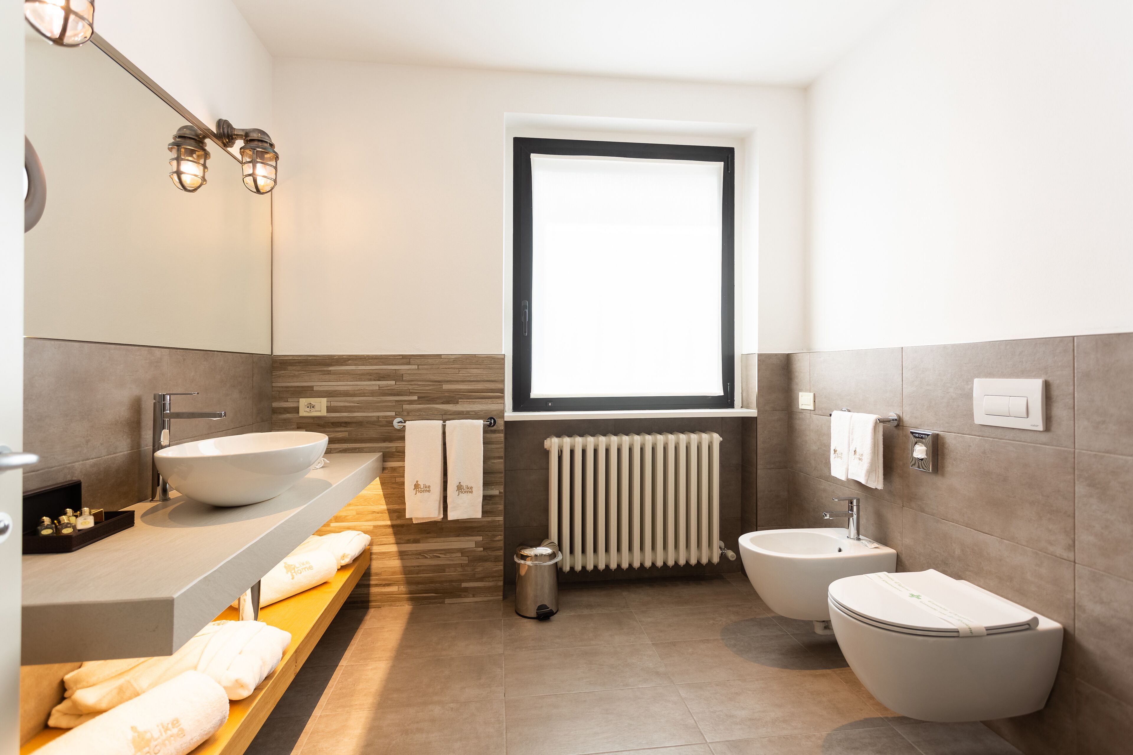 A modern bathroom with a large sink, bidet, and a window.