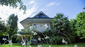 A house with a balcony, surrounded by lush greenery and a well-maintained lawn. - Like Home - Boutique Hotel (Azzano San Paolo)