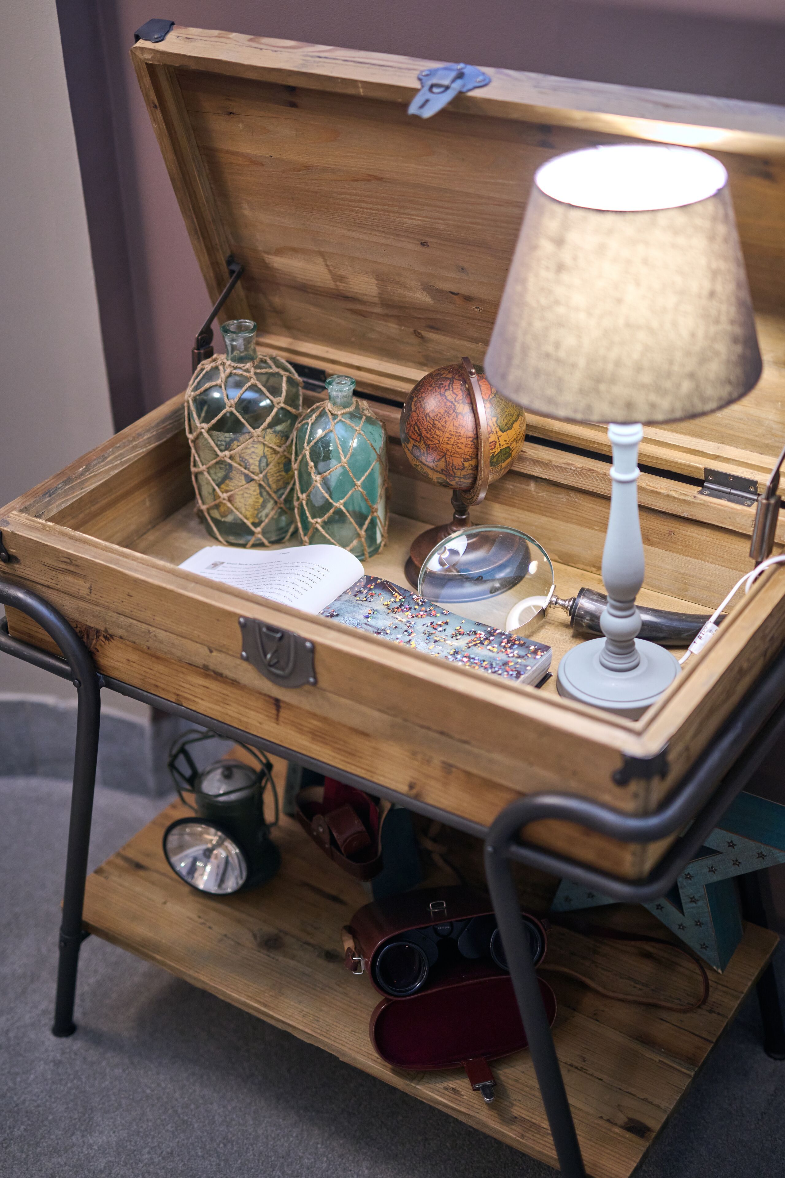 Un coffre en bois contenant une lampe, un globe terrestre et divers objets décoratifs.