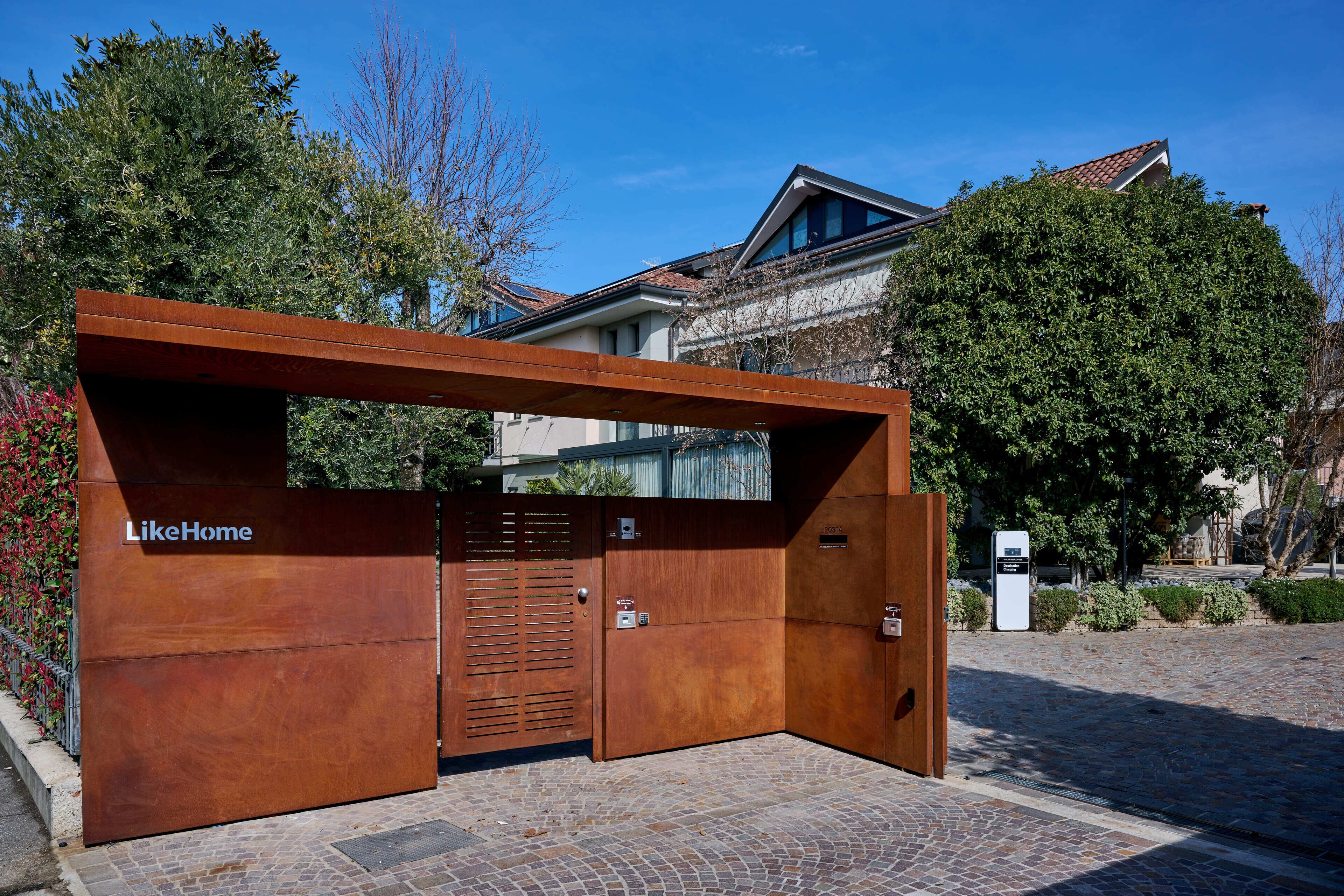 Un edificio moderno con un'ampia entrata in legno e un'insegna che riporta la scritta 'LikeHome'.