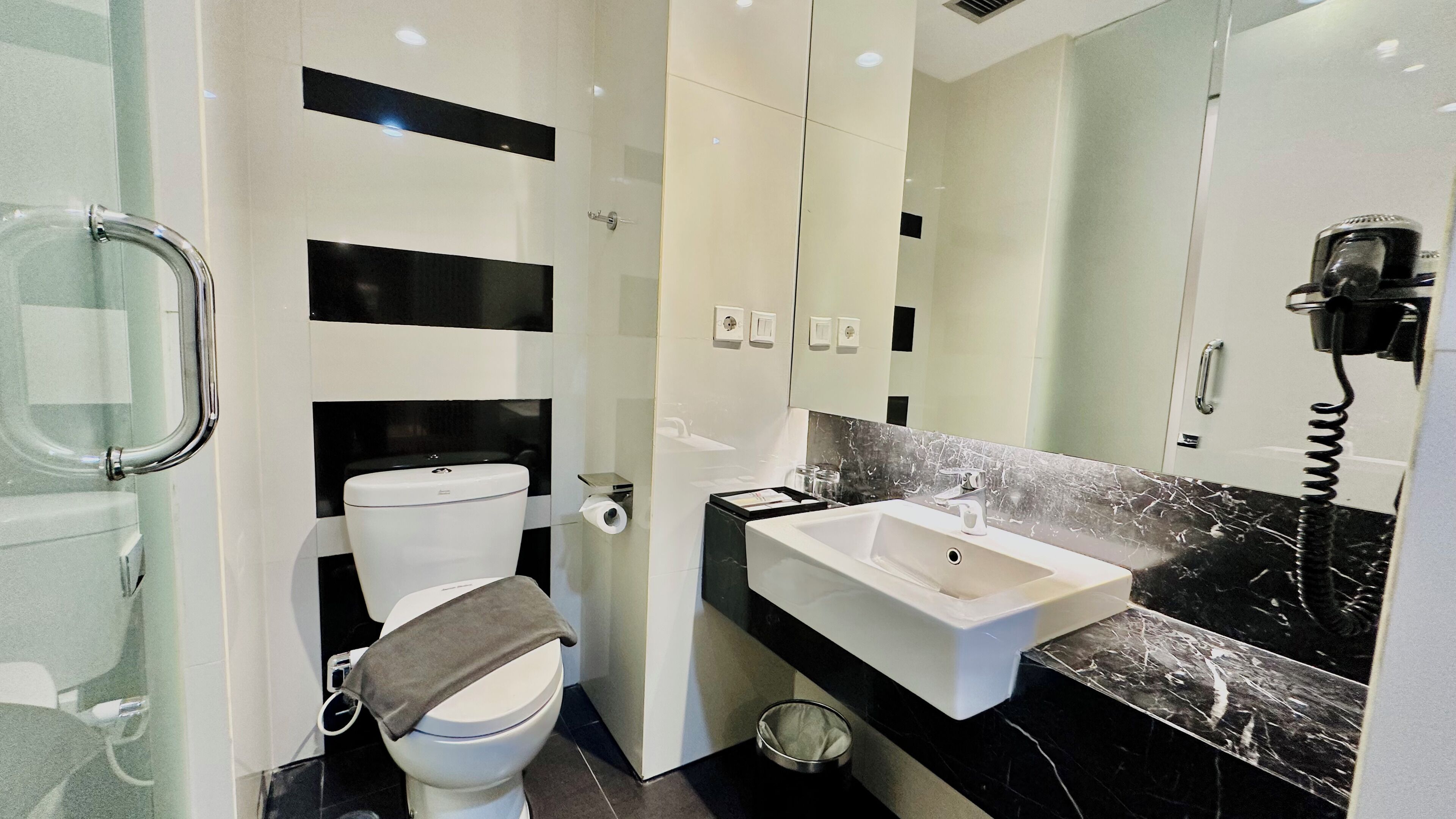 A modern bathroom with a toilet, sink, and mirror.