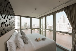 Ein Hotelzimmer mit einem großen Bett, Blick auf eine Stadtlandschaft und einer dekorativen Wandverkleidung.