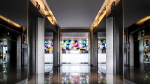 A modern hotel lobby with a reflective floor, a central stained glass window, and clear signage for low and high zones. - Klapsons The River Residences Bangkok (Bangkok)