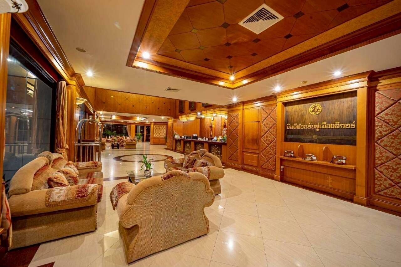 A spacious lobby with a reception desk, seating area, and a decorative wall with a logo.