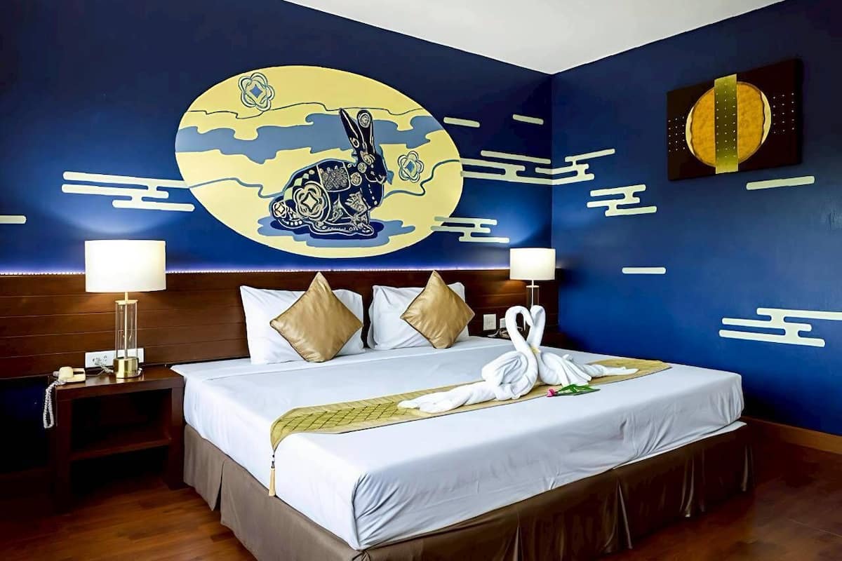 A hotel room with a large bed, two bedside tables, a wall mural, and a nightstand.