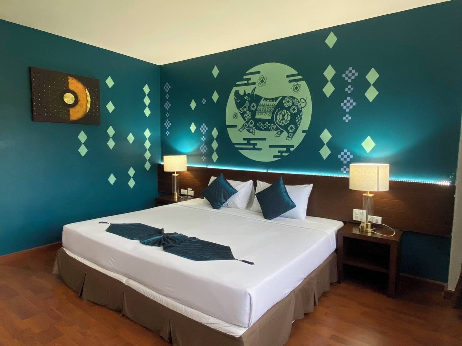 Ein Hotelzimmer mit einem großen Bett, zwei Nachttischen, einem Wandgemälde und einem Holzboden.