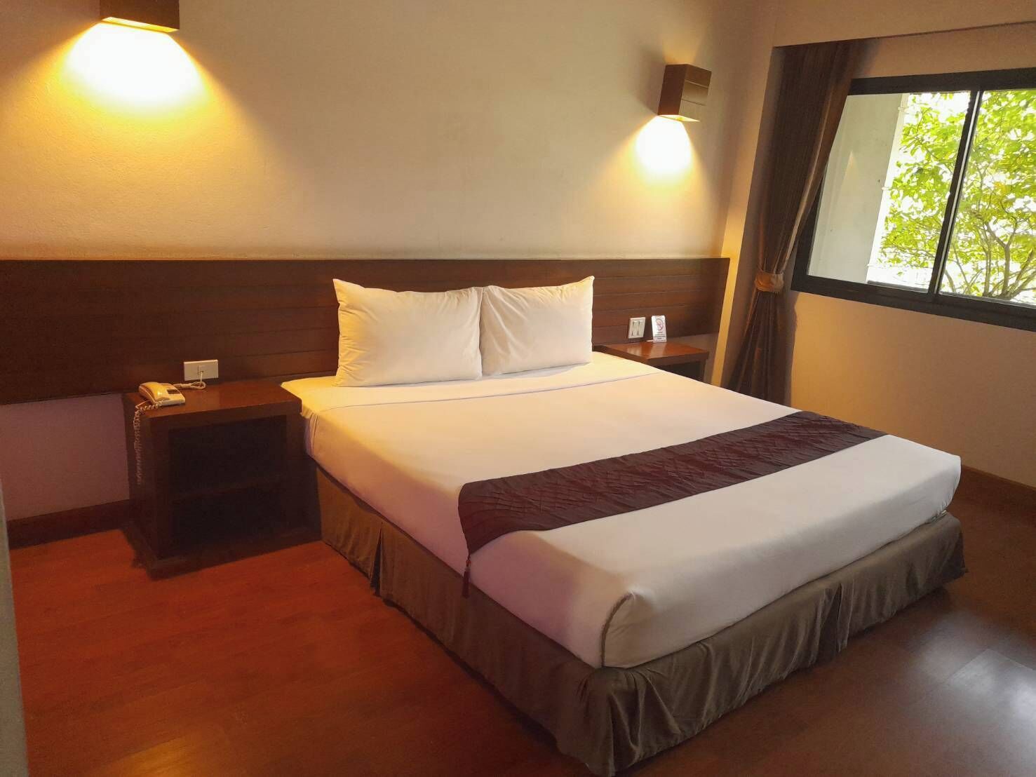A hotel room with a bed, bedside tables, a phone, and a window with curtains.