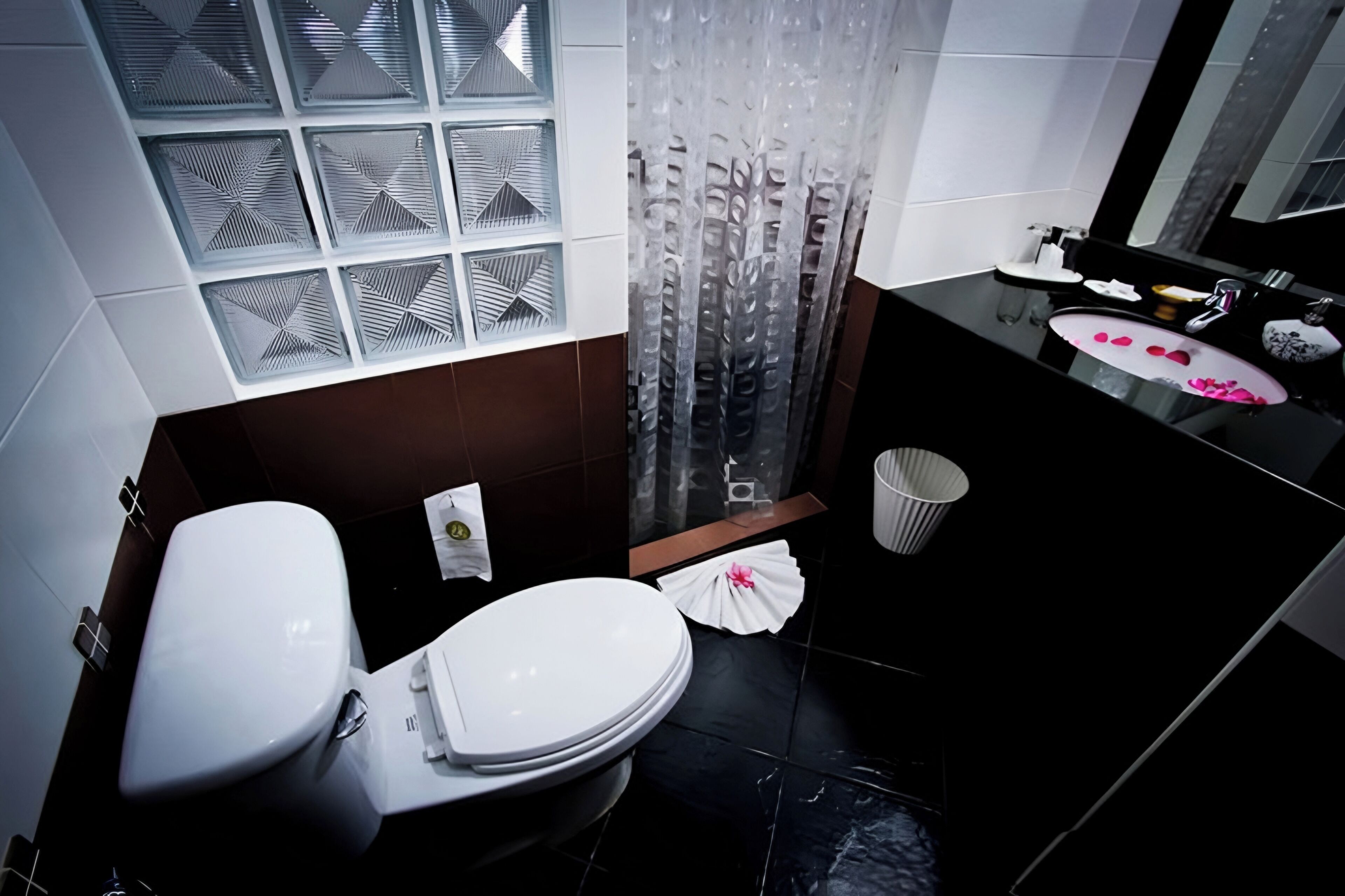 Un baño con inodoro, lavamanos, espejo y cortina de ducha.