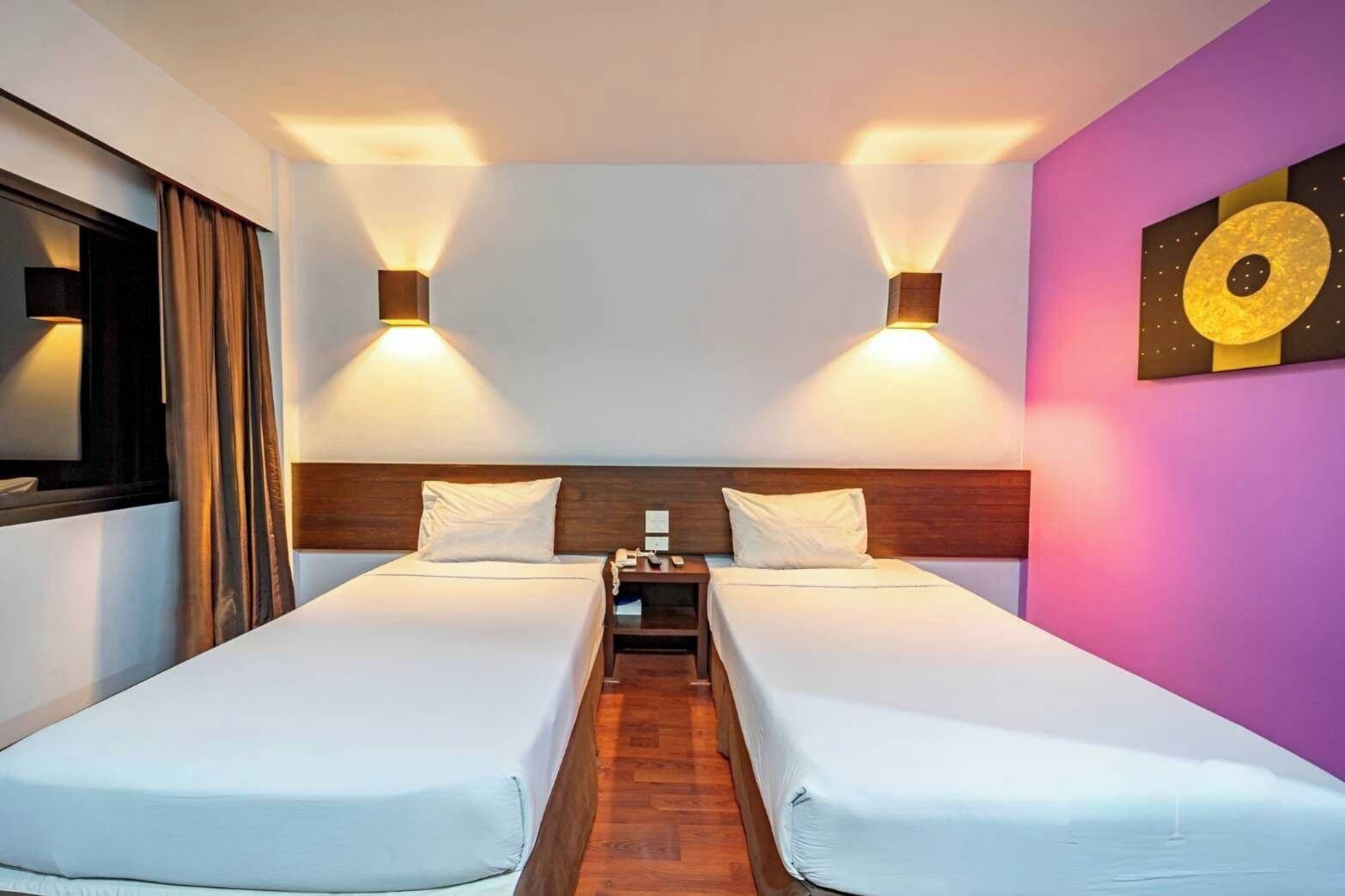 Habitación doble con dos camas, una mesita de noche, una lámpara de pared y un cuadro.