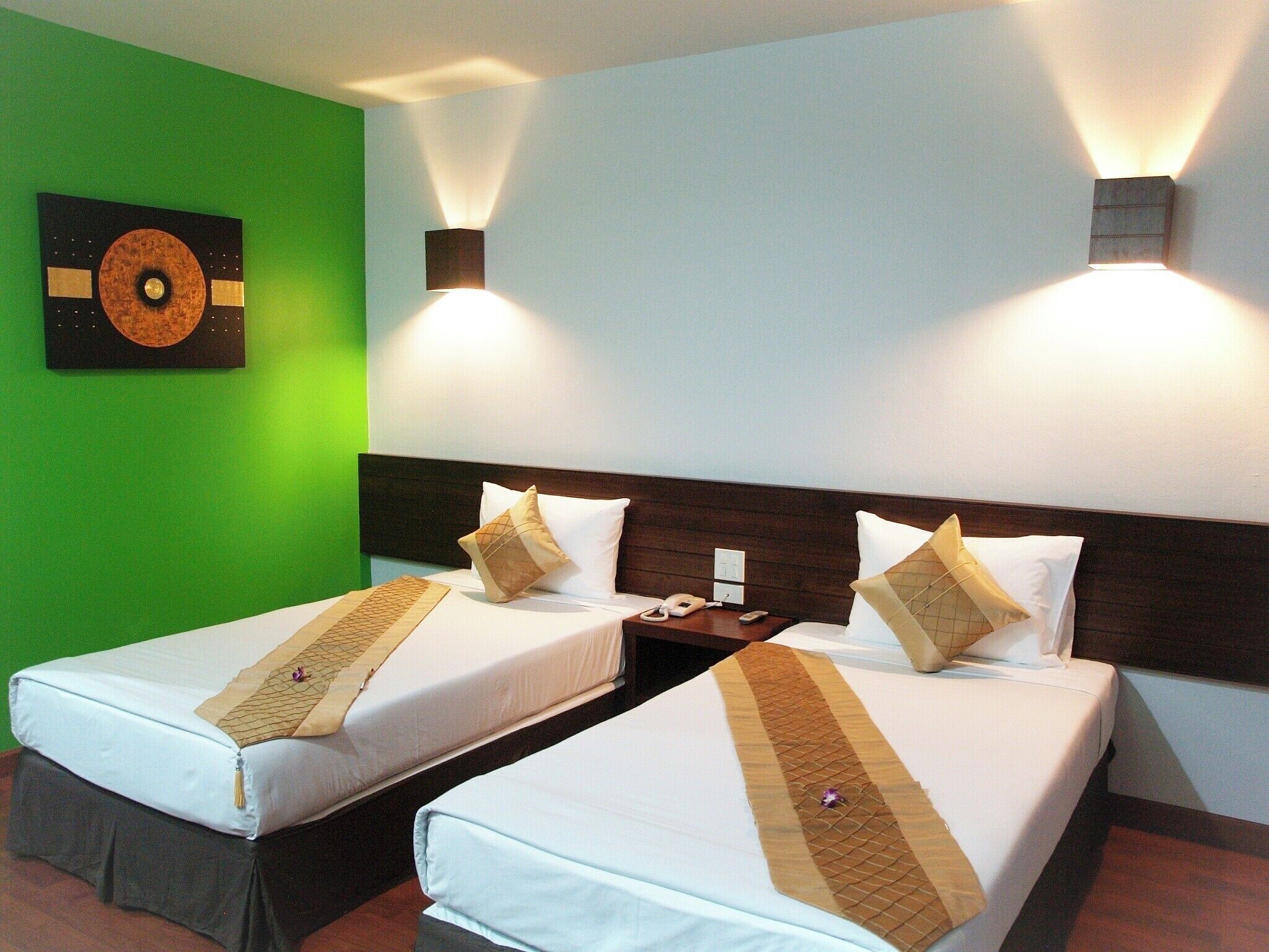 A hotel room with two beds, a green wall, and a wall-mounted artwork.