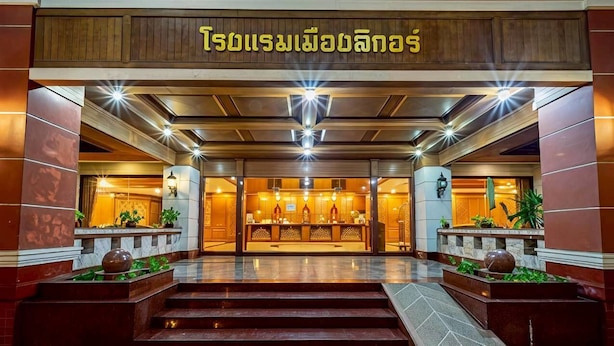 Entrada de un hotel con mostrador de recepción, escalones que conducen a él y un cartel arriba.
