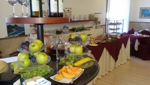 Een buffetopstelling met meerdere fruit schalen, een wijnkeuze en diverse gerechten op een tafel.