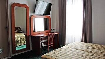 Ein Hotelzimmer mit Bett, Schreibtisch, Stuhl, Fernseher auf einem Standfuß und einem großen Spiegel.