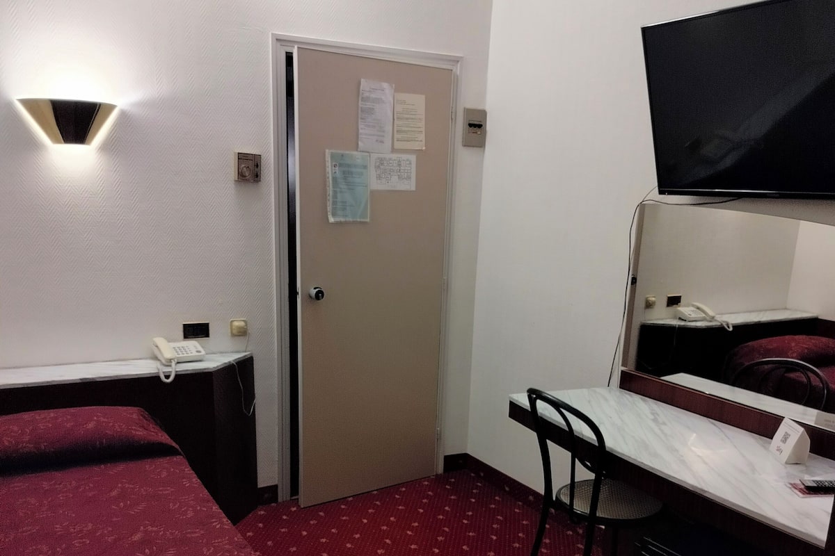 A hotel room with two beds, a desk, a chair, a television, and a minibar.