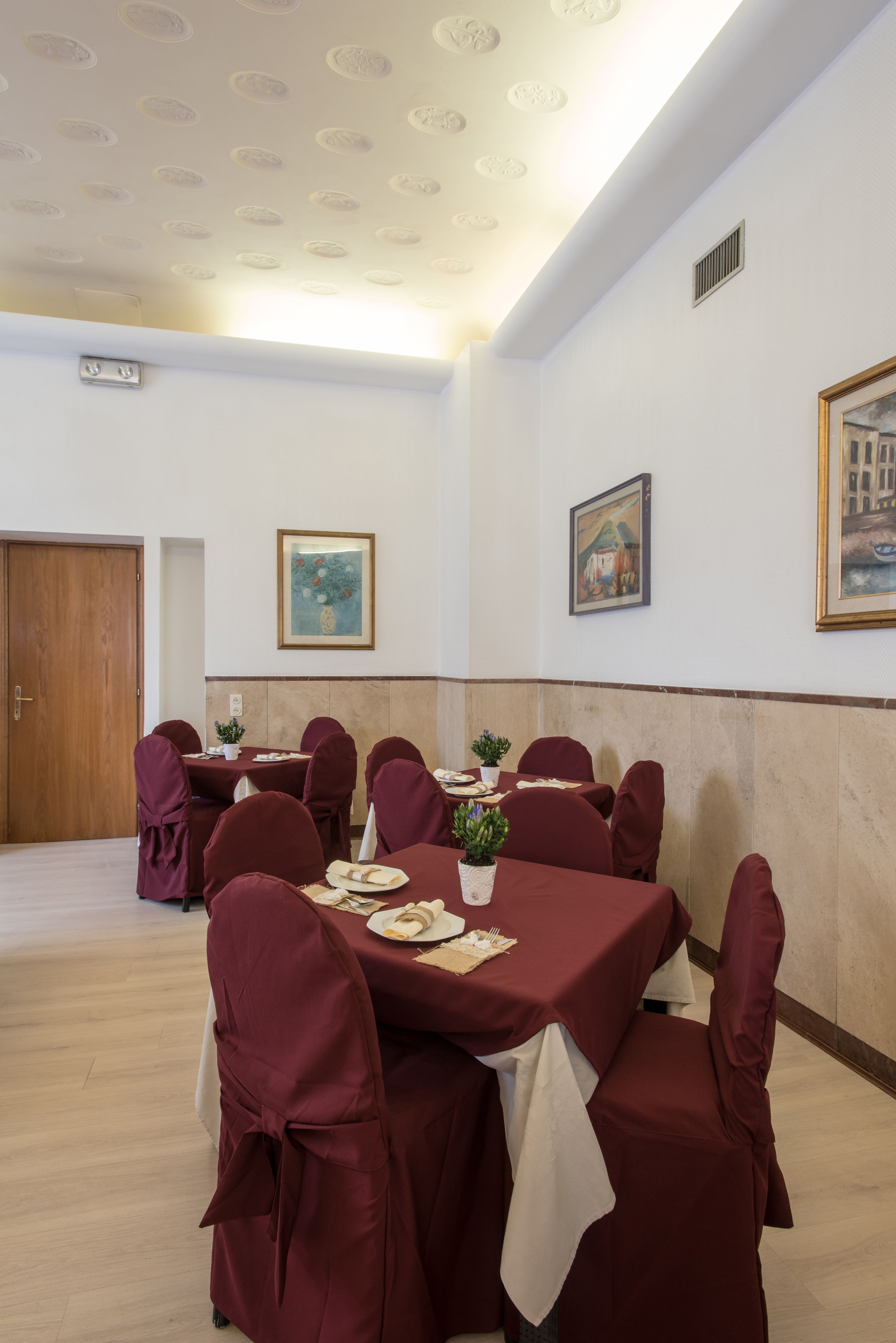 A conference room with round tables, red chairs, and white tablecloths.