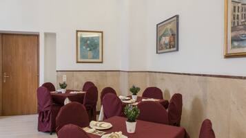 A conference room with round tables, red chairs, and white tablecloths.