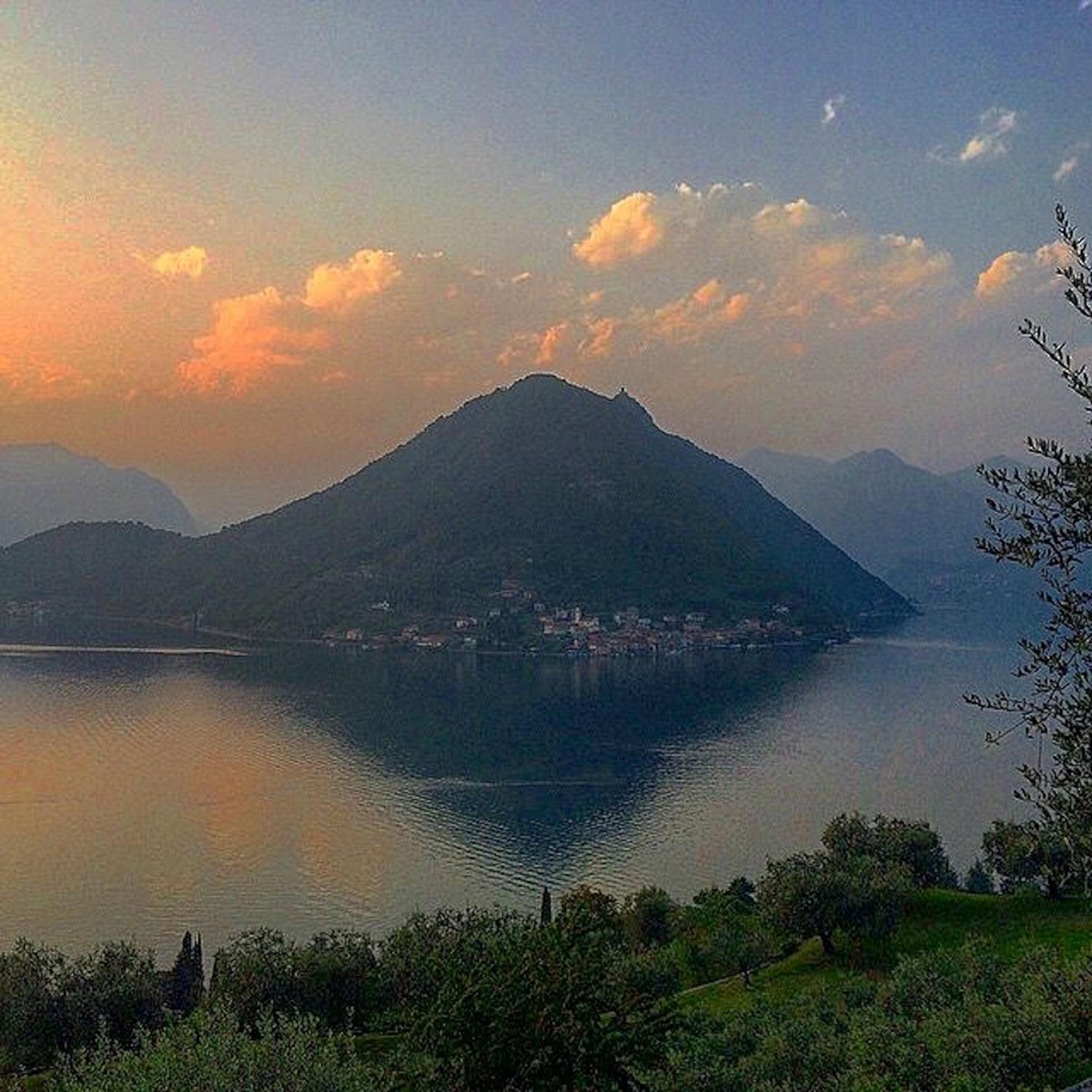 A mountain with a lake in the foreground and a small settlement at its base.