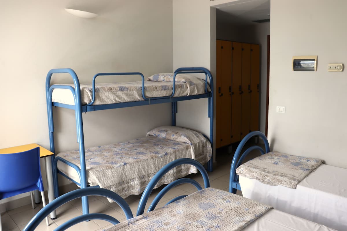 Ein Schlafsaalzimmer mit Etagenbetten, einem kleinen Tisch und Stühlen.