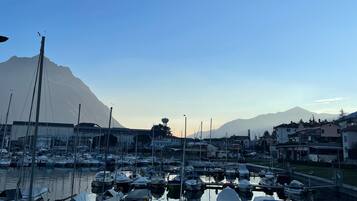 A marina with boats docked, a mountain in the background, and buildings along the waterfront.