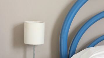 A bed with a blue headboard, a bedside table with a lamp, and a white pillow.