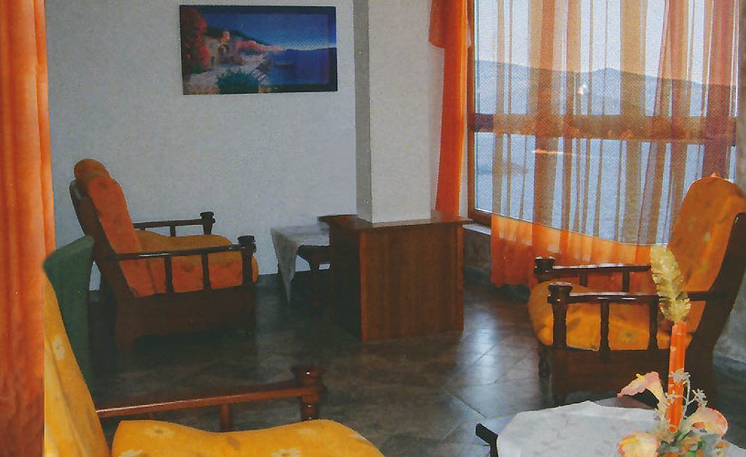 A room with two wooden chairs, a small table, and a painting on the wall.