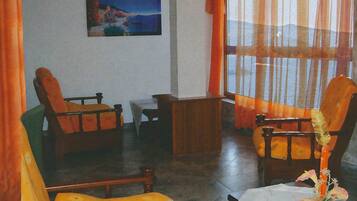 A room with two wooden chairs, a small table, and a painting on the wall.