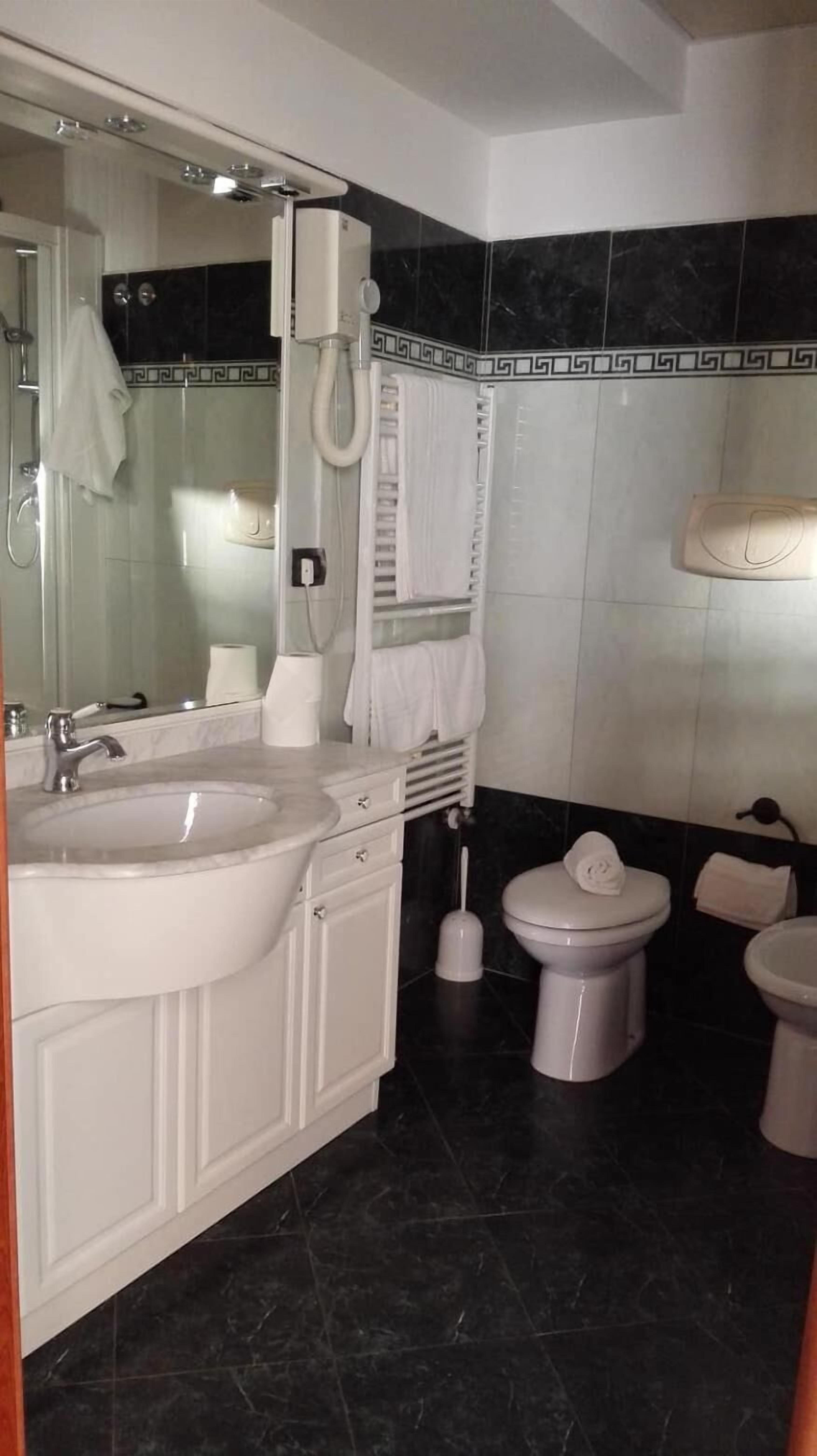 Ein Badezimmer mit Waschbecken, Spiegel, Toilette und Bidet.