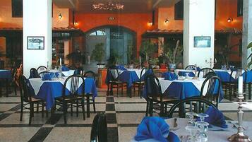A restaurant with tables set for dining, featuring a checkered floor and blue tablecloths.