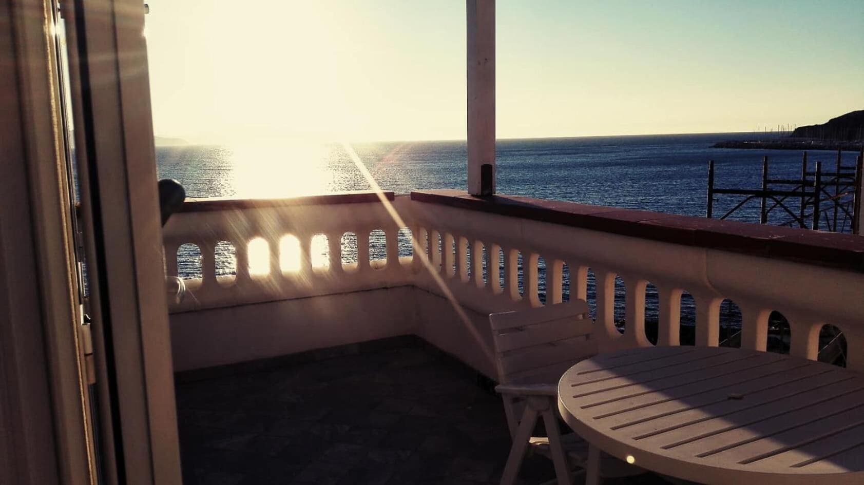 Un balcón con vista al mar, una mesa redonda y una silla.