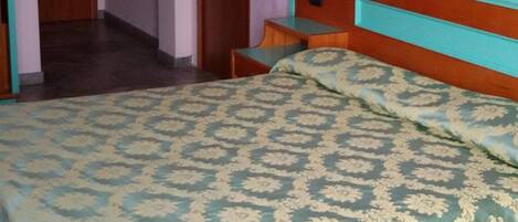 A bedroom with a bed, a nightstand, a door, and a small round table.