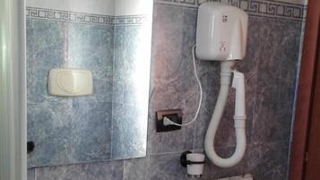 Un baño con lavamanos blanco, un espejo, toallero, calentador y sistema de ventilación.