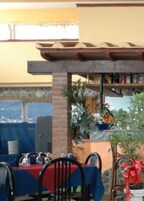 Un área de comedor al aire libre con mesas y sillas, una columna de ladrillo y vistas de la ciudad.