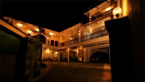 A multi-level building with a covered entrance and a car parked inside. - Hotel Travellers Nest (Kandy)