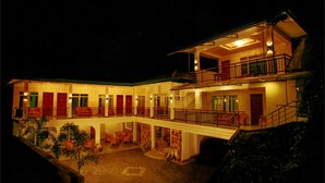 A two-story building with a balcony on the upper floor, a covered outdoor seating area, and a brick courtyard. - Hotel Travellers Nest (Kandy)