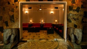 A lobby with a red sofa, two armchairs, a round table, and a mirror reflecting the room. - Hotel Travellers Nest (Kandy)
