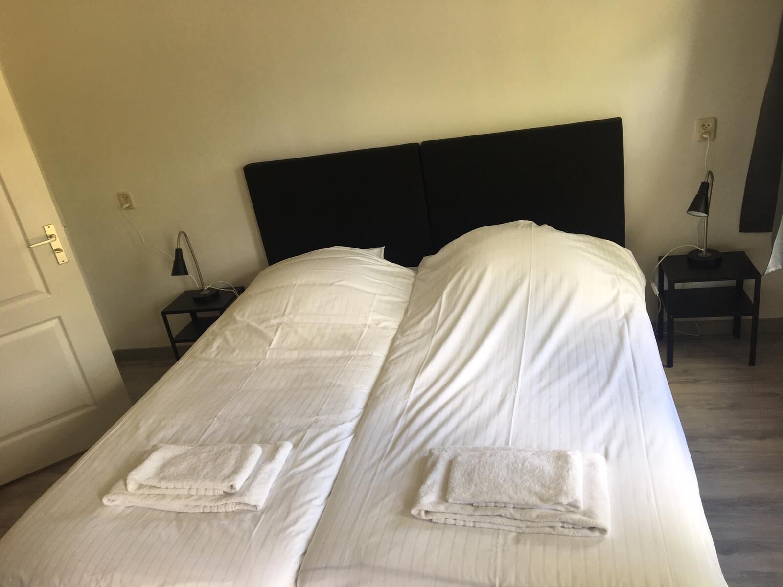 Ein Doppelbett mit weißen Leinentüchern und zwei gefalteten Handtüchern.