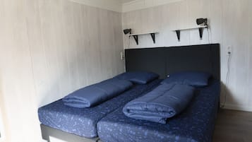 Un lit double avec une tête de lit sombre et un mur de couleur claire.