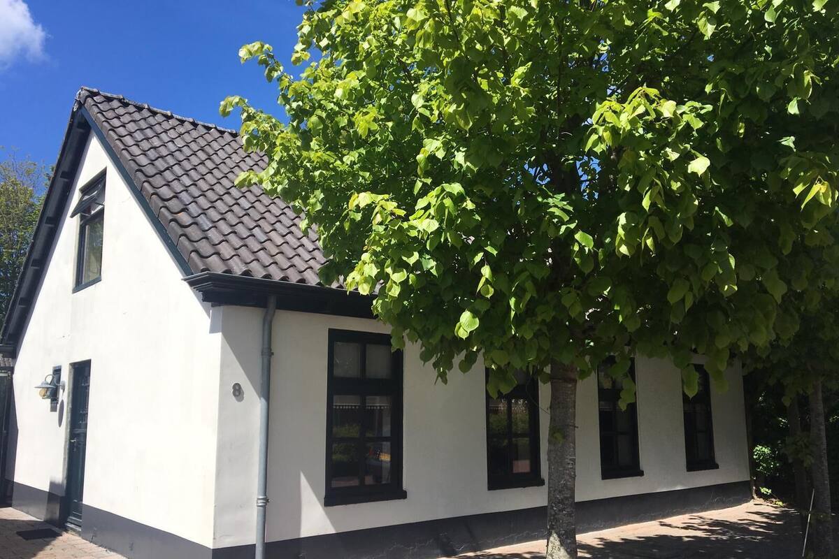 Ein weißes Gebäude mit dunklem Dach, schwarzen Fensterrahmen und der deutlich sichtbaren Nummer 8 an der Seite.