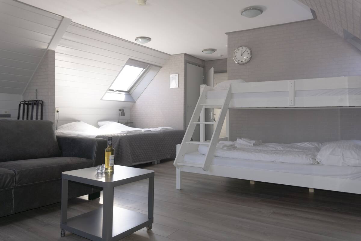 Ein Schlafzimmer mit einem Etagenbett, einer Schlafcouch, einem kleinen Tisch und einem Fenster.
