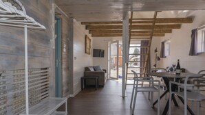 Un intérieur moderne avec un plancher en bois, un coin repas comprenant une table et des chaises, un canapé et un téléviseur fixé au mur.