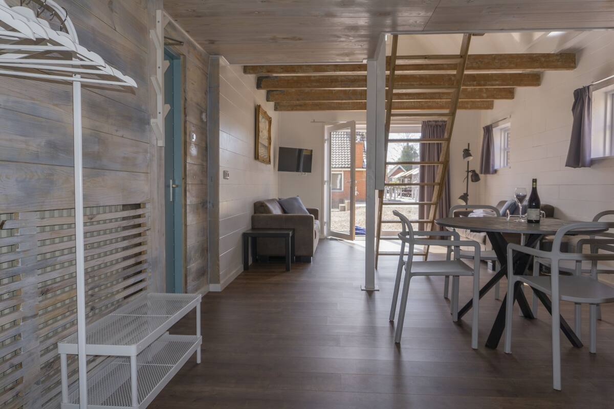 Ein modernes Interieur mit Holzboden, einer Essecke mit Tisch und Stühlen, einer Couch und einem an der Wand befestigten Fernseher.