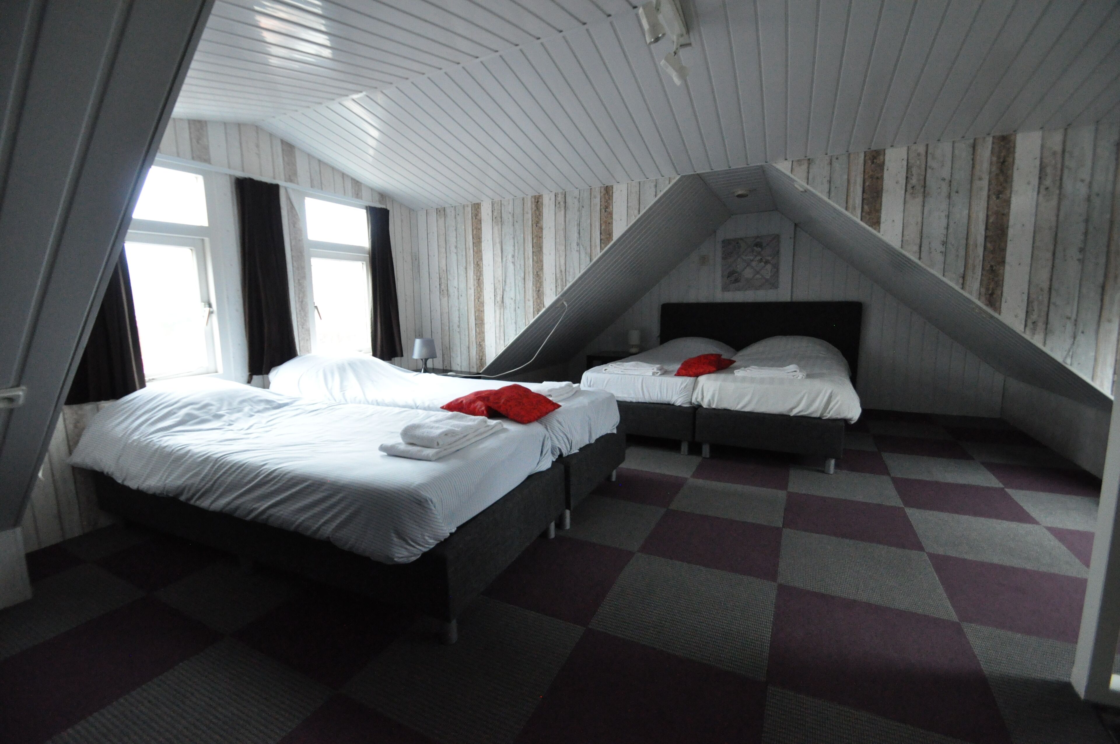 A room with two beds, a checkered floor, and a sloped ceiling.