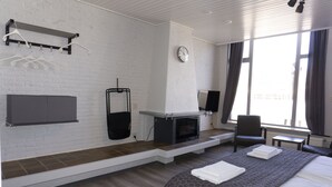 Une chambre d’hôtel avec une cheminée, un lit, une chaise, une télévision et une fenêtre avec des rideaux.